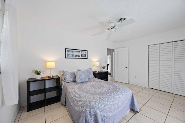 bedroom featuring light tile patterned flooring, ceiling fan, a closet, and a textured ceiling