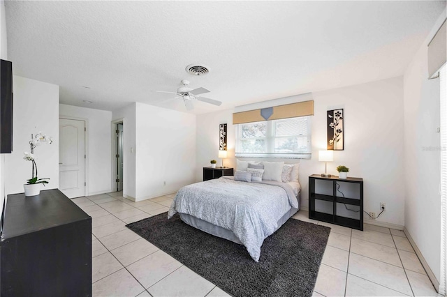 tiled bedroom with ceiling fan and a textured ceiling