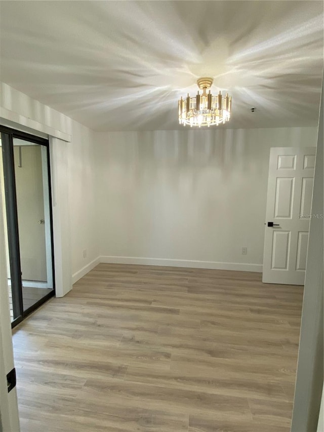 unfurnished room with a chandelier and light wood-type flooring