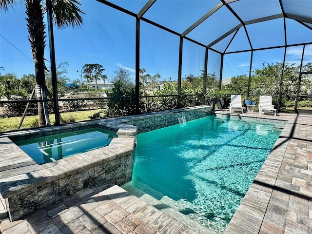 view of pool featuring an in ground hot tub, pool water feature, a patio, and glass enclosure