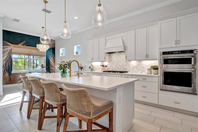 kitchen featuring a kitchen island with sink, double oven, white cabinetry, and custom exhaust hood