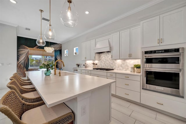 kitchen featuring pendant lighting, sink, appliances with stainless steel finishes, a kitchen island with sink, and white cabinets