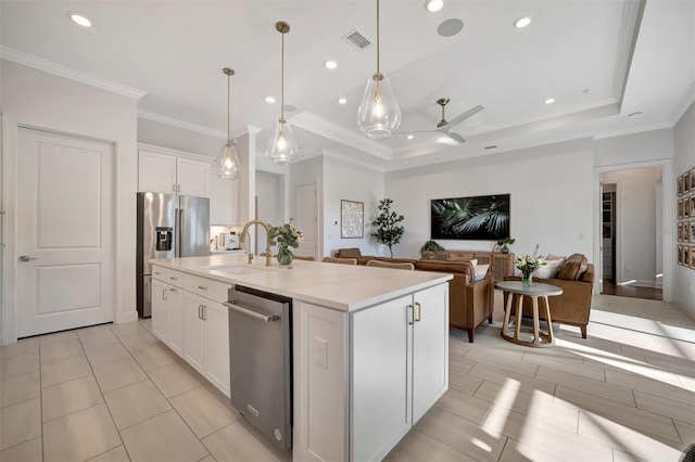 kitchen with appliances with stainless steel finishes, decorative light fixtures, white cabinetry, sink, and a kitchen island with sink