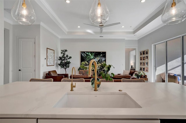 kitchen featuring crown molding, decorative light fixtures, a raised ceiling, and sink