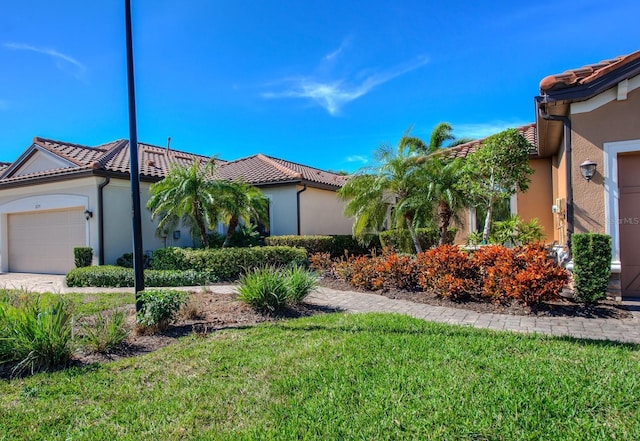 mediterranean / spanish-style house featuring a garage and a front lawn