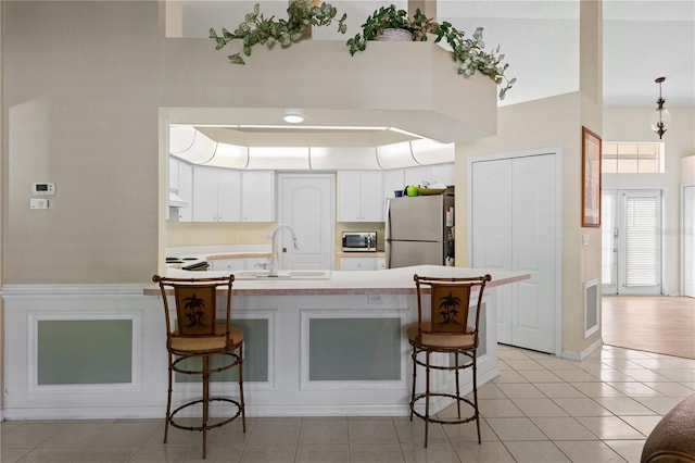 kitchen with stainless steel appliances, sink, a breakfast bar area, and white cabinets