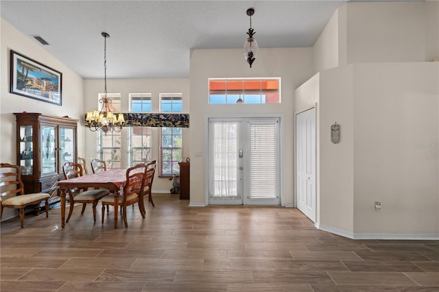 dining space featuring french doors, a chandelier, and a high ceiling