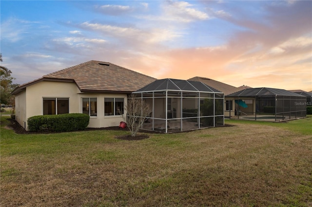 back house at dusk featuring a yard and a lanai