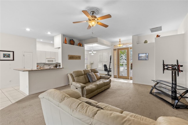 living room with ceiling fan with notable chandelier and light carpet