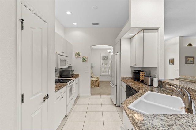 kitchen featuring sink, white appliances, dark stone countertops, white cabinets, and light tile patterned flooring