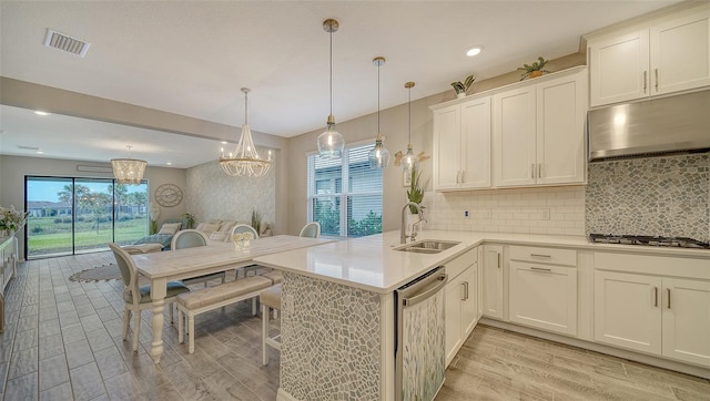 kitchen with appliances with stainless steel finishes, white cabinetry, sink, hanging light fixtures, and kitchen peninsula