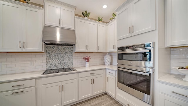 kitchen featuring white cabinetry, light stone counters, light hardwood / wood-style flooring, stainless steel appliances, and backsplash