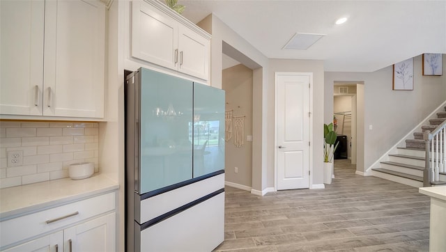 kitchen with white cabinetry, decorative backsplash, white fridge, and light hardwood / wood-style flooring