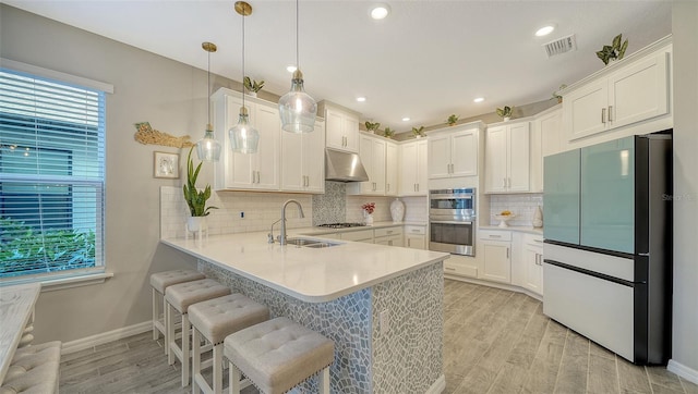 kitchen featuring white cabinetry, sink, decorative light fixtures, and stainless steel appliances