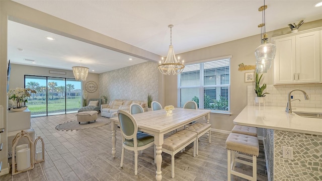 dining area featuring beamed ceiling, a chandelier, sink, and light wood-type flooring