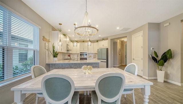 dining area with plenty of natural light, a chandelier, and light hardwood / wood-style floors