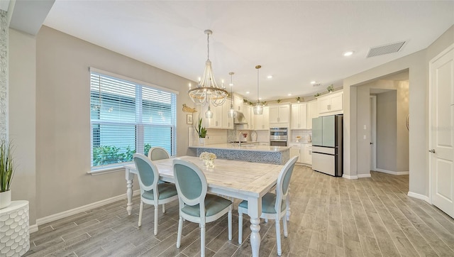 dining area featuring sink, a chandelier, and light wood-type flooring