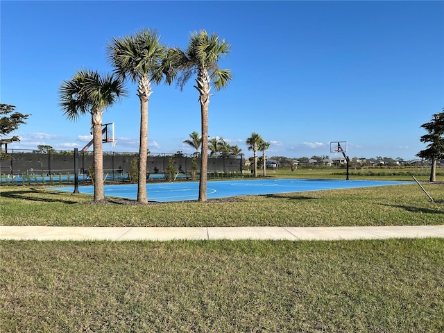 view of basketball court featuring a lawn and a water view