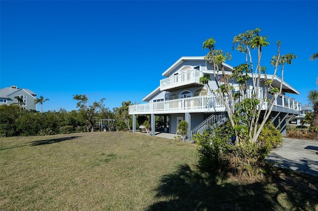 rear view of property featuring a balcony and a yard