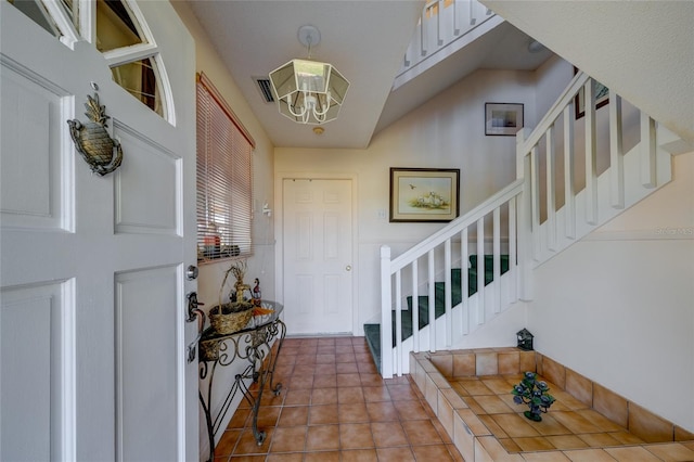 tiled foyer with a chandelier