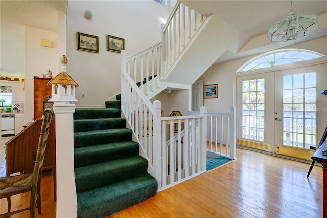 interior space featuring lofted ceiling, a notable chandelier, wood-type flooring, and french doors