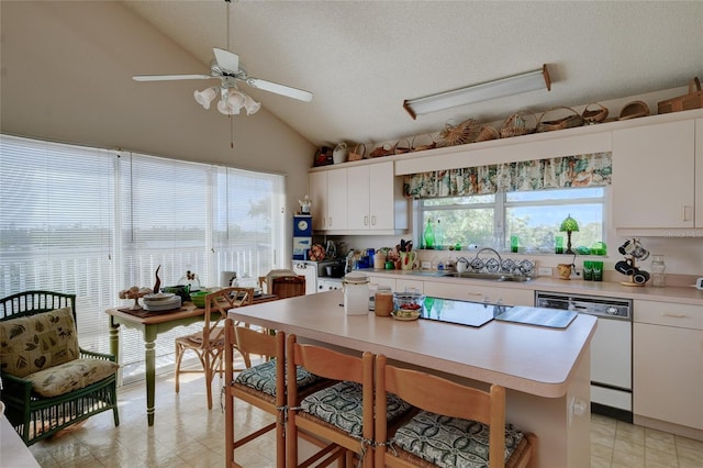 kitchen featuring sink, white cabinetry, a center island, white dishwasher, and vaulted ceiling