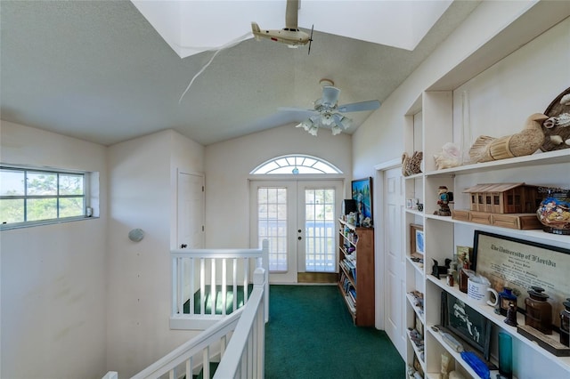 hall with dark colored carpet, lofted ceiling, a textured ceiling, and french doors