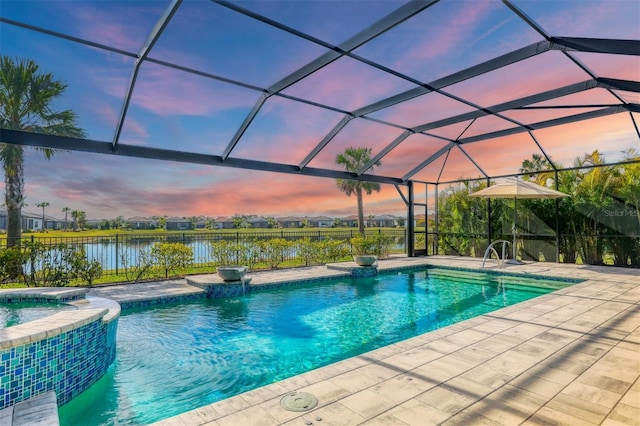 pool at dusk featuring a water view, an in ground hot tub, a lanai, and a patio area