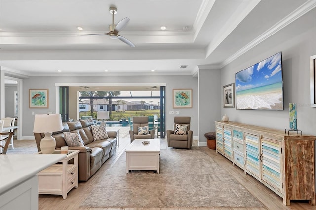 living room featuring a raised ceiling, ornamental molding, light hardwood / wood-style floors, and ceiling fan