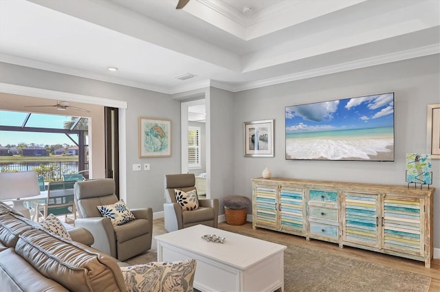 living room featuring a tray ceiling, ornamental molding, and light hardwood / wood-style floors