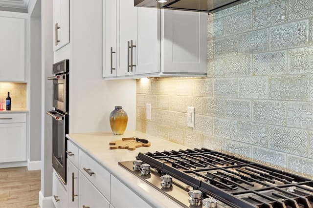 kitchen featuring white cabinetry, decorative backsplash, light hardwood / wood-style flooring, and appliances with stainless steel finishes