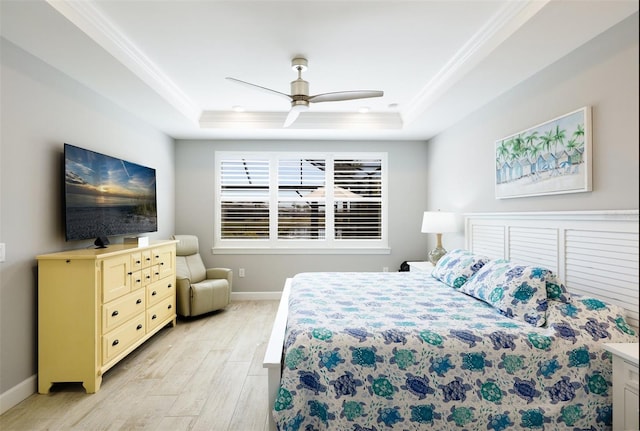 bedroom with crown molding, a tray ceiling, ceiling fan, and light wood-type flooring