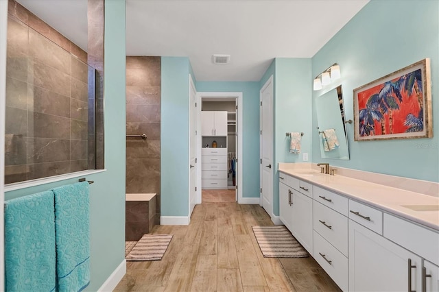 bathroom featuring vanity, wood-type flooring, and tiled shower