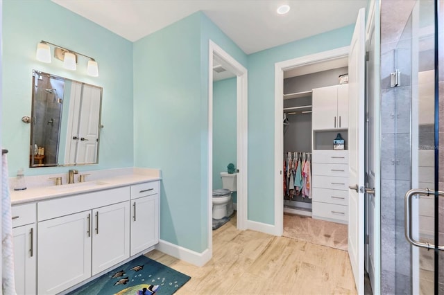 bathroom with an enclosed shower, vanity, hardwood / wood-style flooring, and toilet