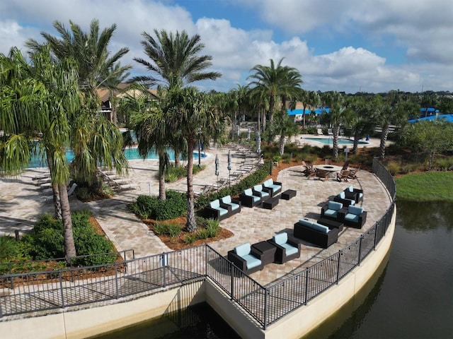 view of community featuring a swimming pool, an outdoor fire pit, a patio area, and a water view