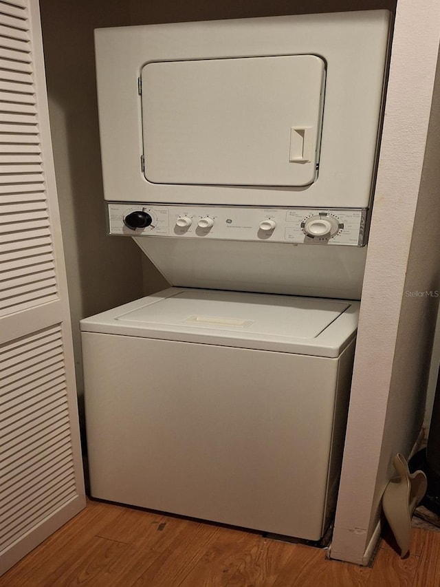 laundry room featuring stacked washer and dryer and light hardwood / wood-style flooring