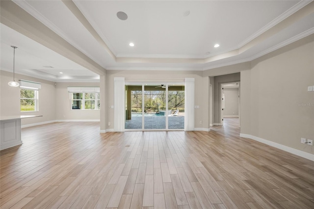 unfurnished living room with crown molding, a tray ceiling, and light wood-type flooring