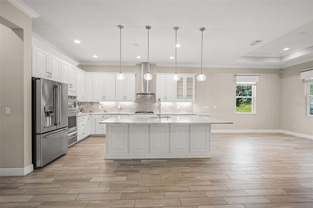 kitchen featuring white cabinetry, a kitchen island with sink, wall chimney exhaust hood, and appliances with stainless steel finishes