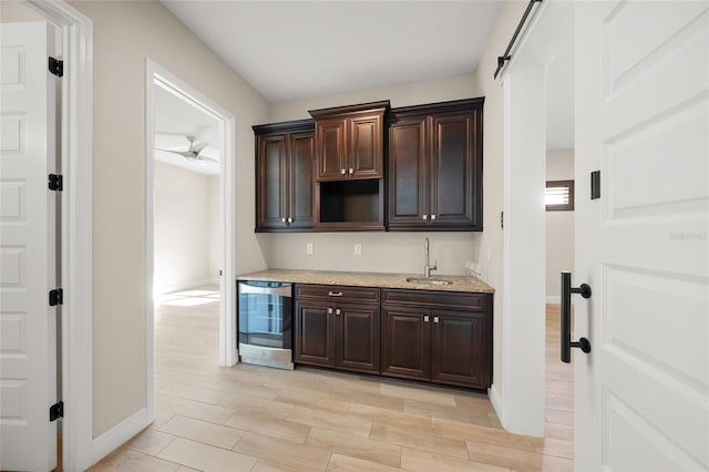 kitchen featuring wine cooler, dark brown cabinetry, a barn door, and sink