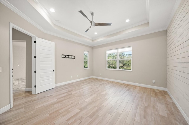 empty room featuring crown molding, light hardwood / wood-style flooring, ceiling fan, and a tray ceiling