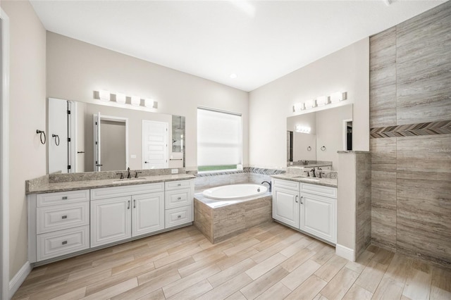 bathroom with vanity, wood-type flooring, and tiled bath