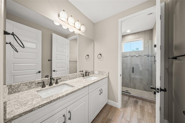 bathroom with a shower with door, vanity, and wood-type flooring