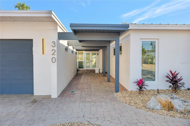 view of exterior entry with a garage and french doors