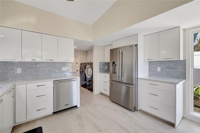 kitchen featuring white cabinetry, backsplash, washer and clothes dryer, and stainless steel appliances