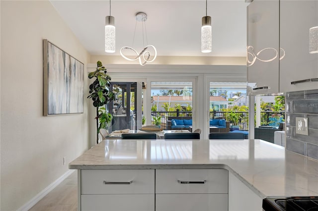 kitchen with pendant lighting, light stone counters, and white cabinets