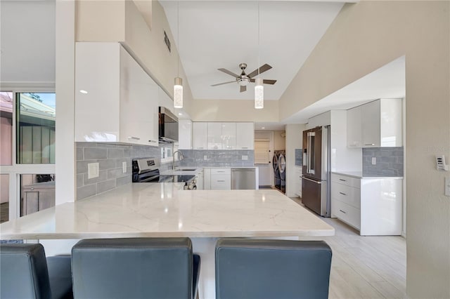 kitchen featuring stainless steel appliances, kitchen peninsula, and white cabinets