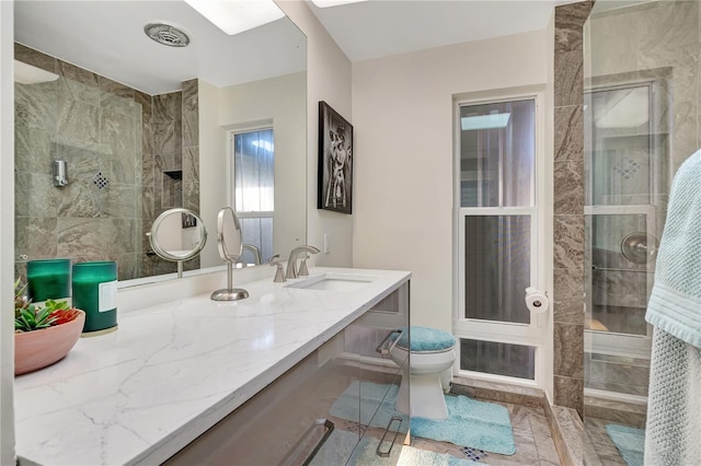 bathroom with tiled shower, vanity, and toilet