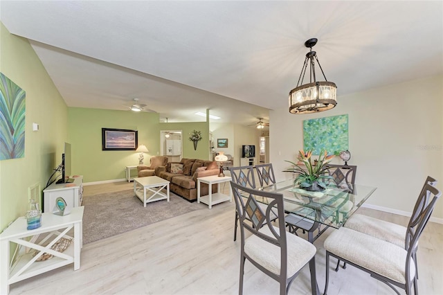 dining space with ceiling fan with notable chandelier and light hardwood / wood-style flooring