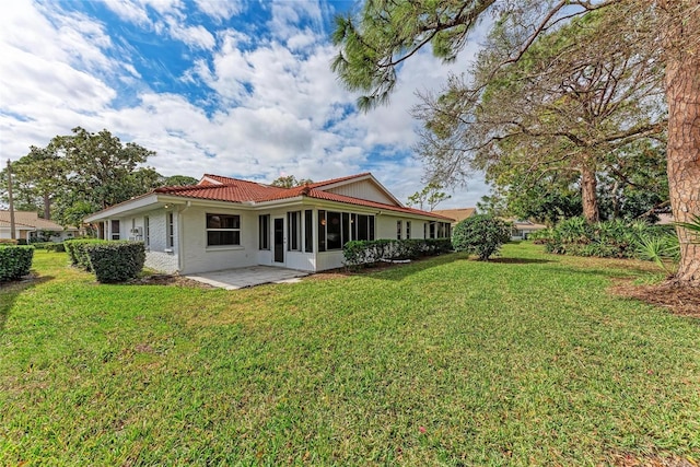 back of house with a sunroom, a lawn, and a patio area