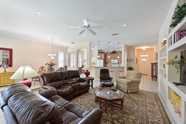 living room featuring built in shelves, ceiling fan with notable chandelier, a textured ceiling, and light tile patterned floors